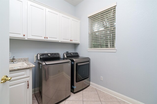 2130 White Eagle Ln, Katy, TX 77450 - washroom with washer and clothes dryer, cabinet space, baseboards, and light tile patterned flooring
