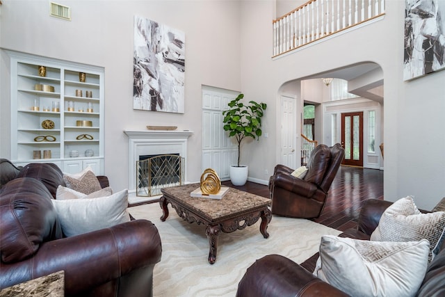 2130 White Eagle Ln, Katy, TX 77450 - living area with wood finished floors, arched walkways, a towering ceiling, baseboards, and a fireplace with raised hearth