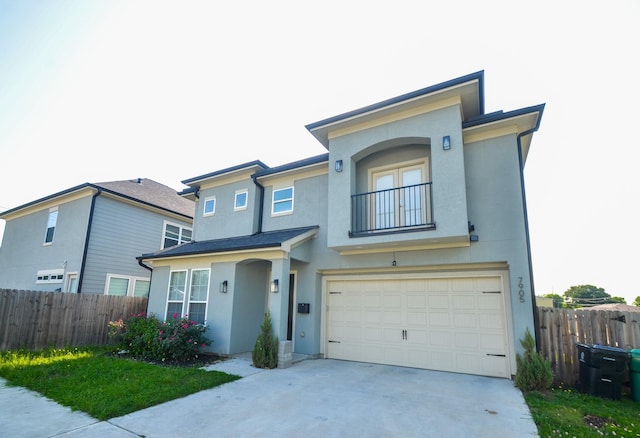 view of front facade with stucco siding, a garage, fence, and concrete driveway