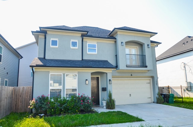 view of front facade with a balcony, stucco siding, fence, a garage, and driveway