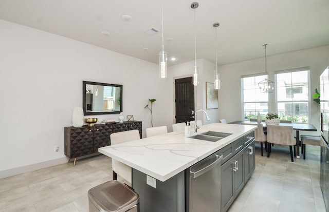 kitchen with a sink, stainless steel dishwasher, pendant lighting, a center island with sink, and a chandelier