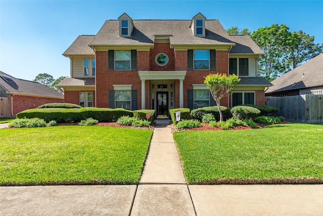 colonial home featuring brick siding and roof with shingles