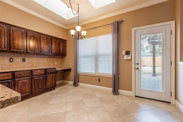 kitchen featuring a skylight, a chandelier, backsplash, crown molding, and healthy amount of natural light