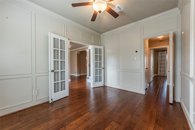 spare room featuring a decorative wall, french doors, crown molding, ceiling fan, and dark wood finished floors