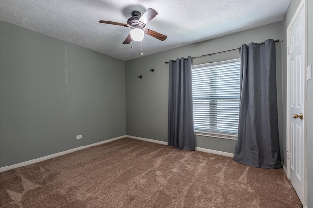 carpeted spare room featuring a textured ceiling, a ceiling fan, and baseboards