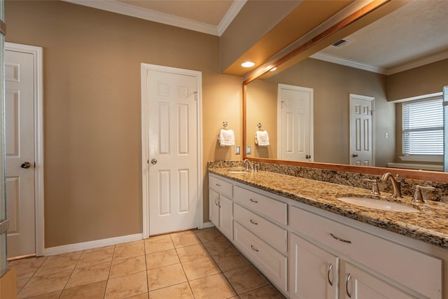 bathroom with crown molding, baseboards, double vanity, and tile patterned floors