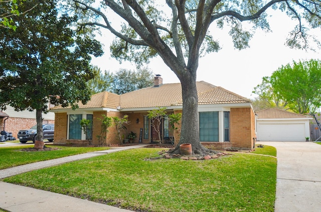 single story home with a tiled roof, a chimney, a front lawn, brick siding, and a detached garage