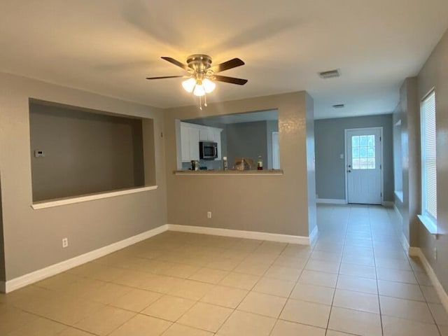 unfurnished room featuring ceiling fan, light tile patterned floors, and baseboards