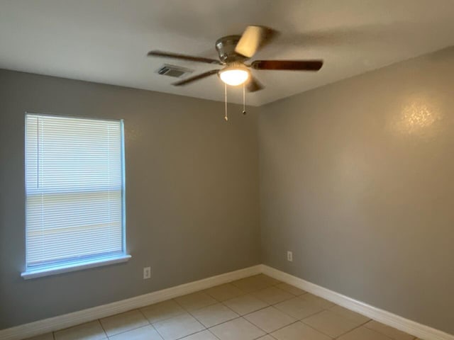 unfurnished room featuring ceiling fan, light tile patterned flooring, and baseboards