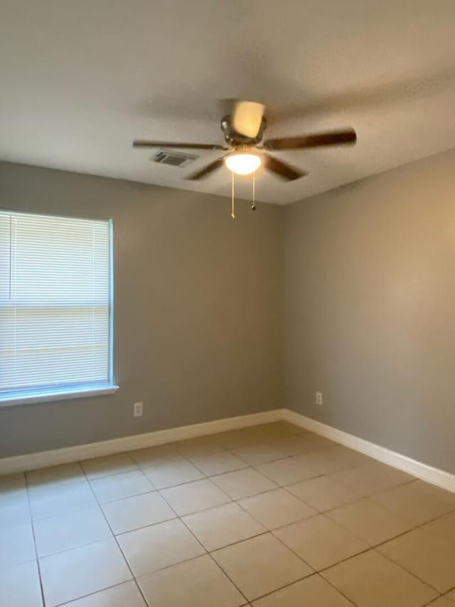 spare room with a ceiling fan, light tile patterned flooring, and baseboards
