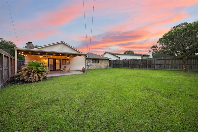 yard at dusk with ceiling fan and a patio area