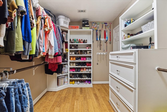 walk in closet with light wood-style floors