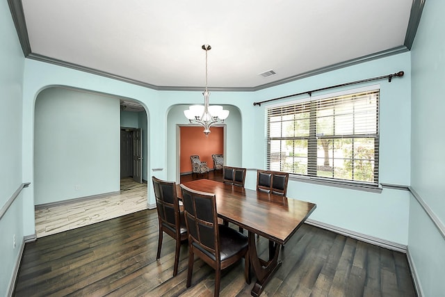 dining area featuring arched walkways, ornamental molding, a chandelier, wood finished floors, and baseboards