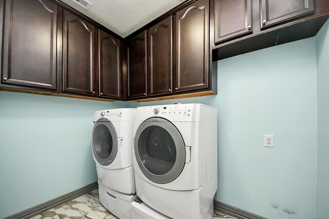 laundry room featuring cabinet space, washer and dryer, light marble finish floors, and baseboards
