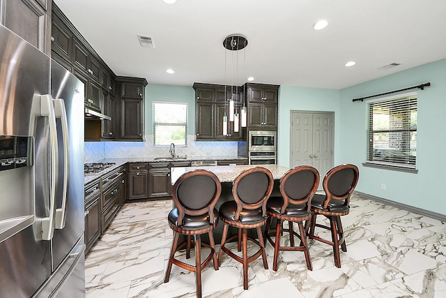 kitchen featuring stainless steel appliances, light marble finish flooring, a sink, recessed lighting, and decorative backsplash
