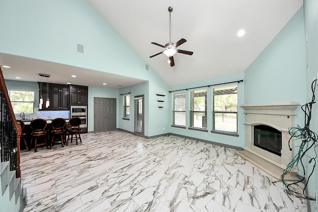 living area featuring a tiled fireplace, a ceiling fan, high vaulted ceiling, recessed lighting, and light marble finish floors