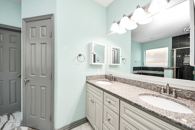 bathroom featuring marble finish floors, a stall shower, double vanity, and baseboards