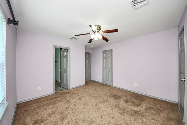 unfurnished bedroom featuring light colored carpet, baseboards, ceiling fan, and ensuite bathroom