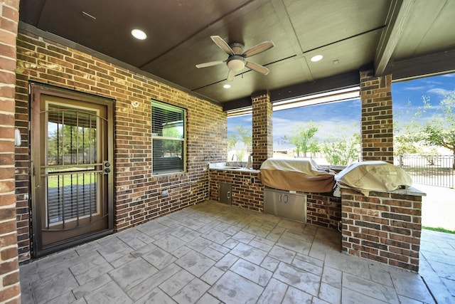 view of patio / terrace featuring exterior kitchen, ceiling fan, fence, a sink, and a grill