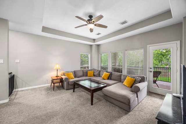 carpeted living room with a tray ceiling, healthy amount of natural light, ceiling fan, and baseboards