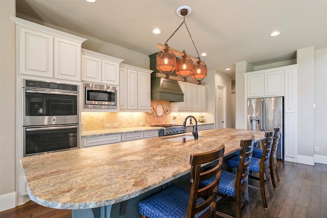 6919 Champion Trl, Katy, TX 77493 - kitchen with appliances with stainless steel finishes, a sink, custom exhaust hood, a breakfast bar area, and baseboards