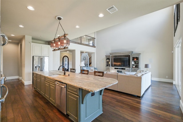 6919 Champion Trl, Katy, TX 77493 - kitchen with stainless steel appliances, a sink, dark wood-style floors, a center island with sink, and a breakfast bar
