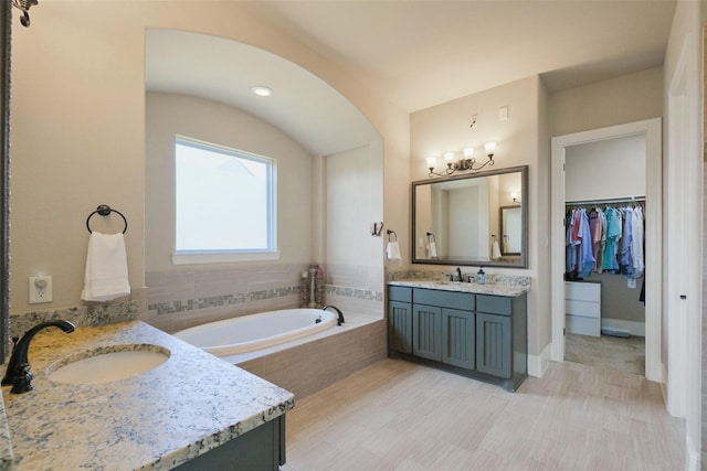 6919 Champion Trl, Katy, TX 77493 - bathroom featuring two vanities, a garden tub, and a walk in closet