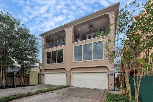 view of front of home with a balcony, ceiling fan, an attached garage, concrete driveway, and stucco siding