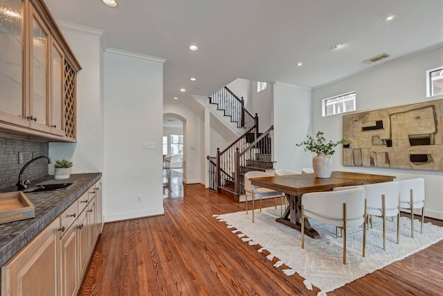 dining room with arched walkways, stairs, dark wood-type flooring, ornamental molding, and baseboards