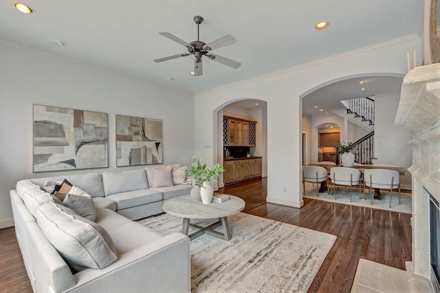 living room featuring arched walkways, wood finished floors, ceiling fan, stairs, and baseboards