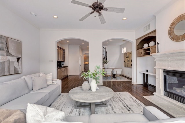 living room featuring arched walkways, wood finished floors, a ceiling fan, crown molding, and recessed lighting
