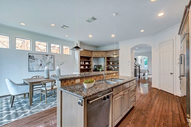 kitchen featuring a sink, arched walkways, dark wood-type flooring, a center island with sink, and stainless steel dishwasher