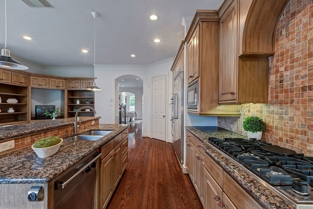 kitchen with a sink, stainless steel appliances, arched walkways, dark stone countertops, and recessed lighting