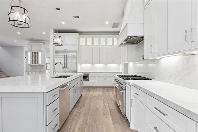 4706 Waring St, Houston, TX 77027 - kitchen with custom range hood, high quality appliances, a sink, tasteful backsplash, and light wood-style flooring