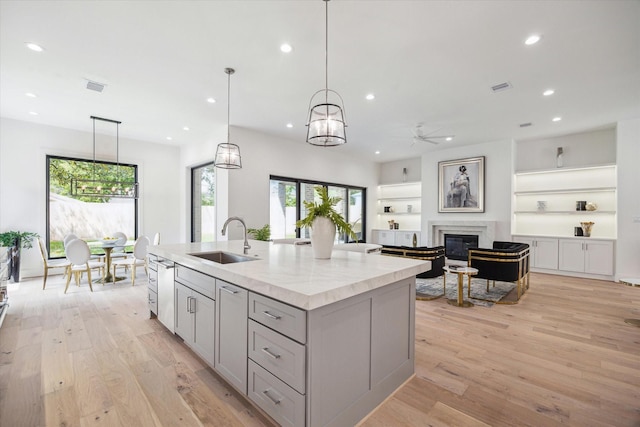 4706 Waring St, Houston, TX 77027 - kitchen featuring a sink, gray cabinets, a ceiling fan, a kitchen island with sink, and light wood-style flooring