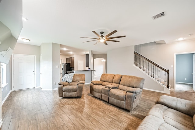 12750 Tullich Ln, Humble, TX 77346 - living room with a ceiling fan, baseboards, light wood-style flooring, stairs, and arched walkways