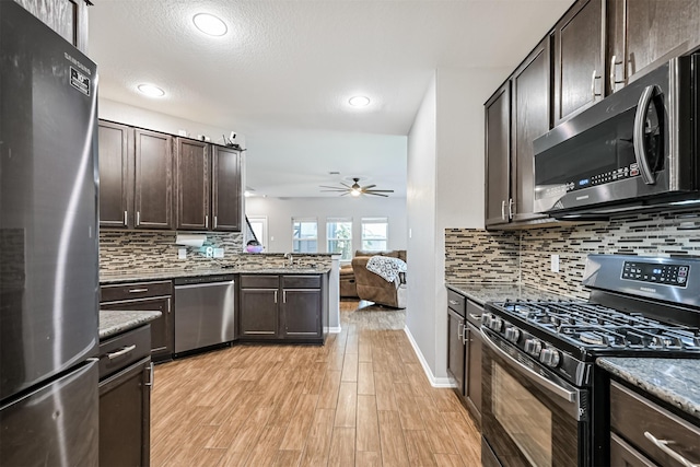 12750 Tullich Ln, Humble, TX 77346 - kitchen with stainless steel appliances, dark brown cabinetry, a ceiling fan, light wood-type flooring, and open floor plan