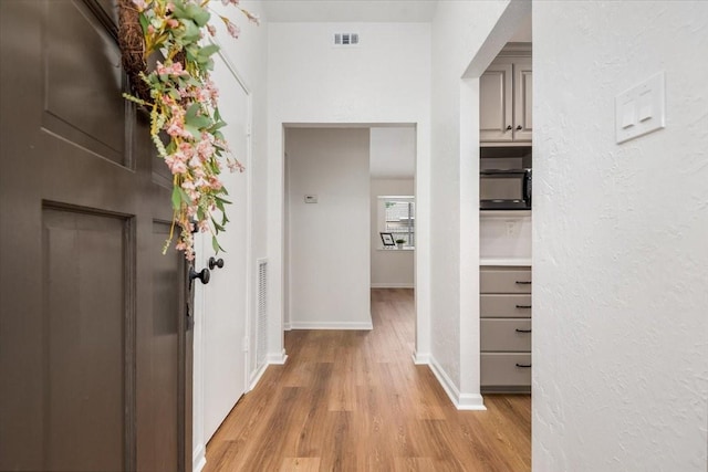 corridor featuring light wood-style floors and baseboards