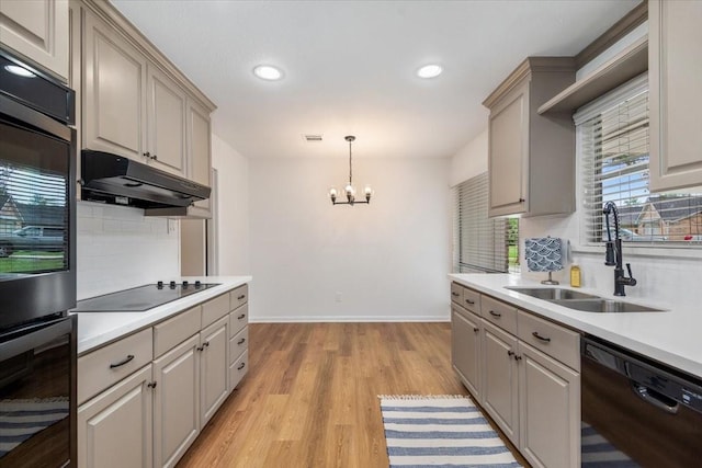 kitchen with black appliances, a sink, light wood-style flooring, backsplash, and baseboards