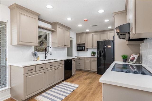 kitchen with black appliances, a sink, extractor fan, tasteful backsplash, and light wood-style floors