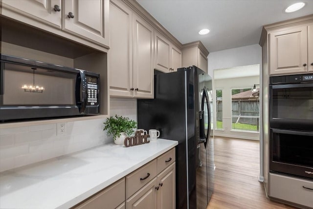 kitchen featuring black appliances, backsplash, light wood-style floors, recessed lighting, and a chandelier