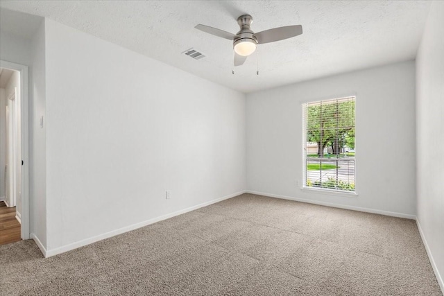 unfurnished room featuring carpet, baseboards, ceiling fan, and a textured ceiling