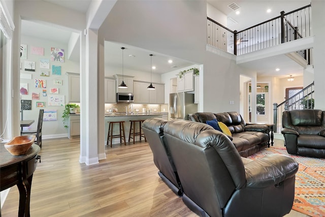 27163 Allenby Park Dr, Magnolia, TX 77354 - living area featuring light wood finished floors, stairs, a high ceiling, baseboards, and recessed lighting