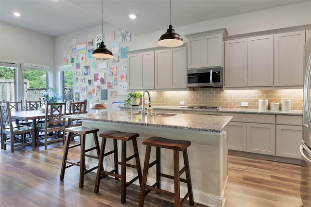 27163 Allenby Park Dr, Magnolia, TX 77354 - kitchen with stainless steel appliances, a sink, light wood-style flooring, tasteful backsplash, and recessed lighting
