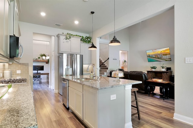 27163 Allenby Park Dr, Magnolia, TX 77354 - kitchen with a sink, backsplash, light wood-type flooring, appliances with stainless steel finishes, and a breakfast bar area