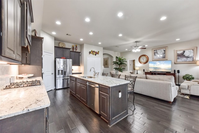 19914 Philippa Hills Trl, Cypress, TX 77433 - kitchen featuring appliances with stainless steel finishes, a sink, open floor plan, ceiling fan, and dark wood-type flooring