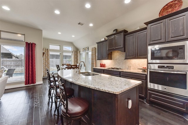19914 Philippa Hills Trl, Cypress, TX 77433 - kitchen featuring stainless steel appliances, a sink, dark wood-style flooring, light stone counters, and an island with sink