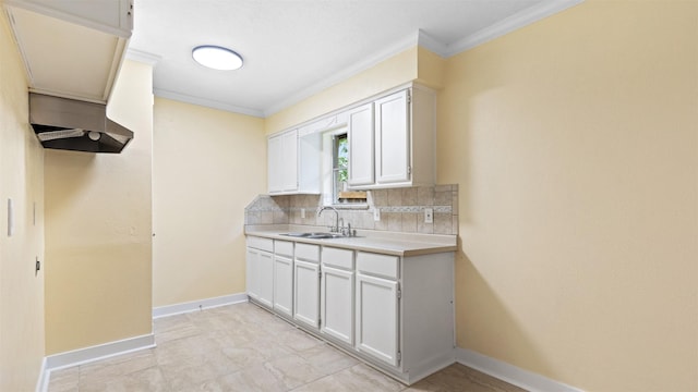 kitchen with a sink, backsplash, crown molding, light countertops, and baseboards