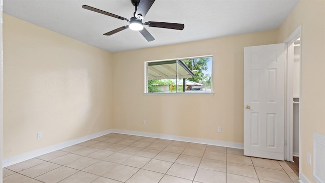 spare room with light tile patterned floors, ceiling fan, and baseboards