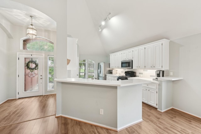 kitchen with appliances with stainless steel finishes, white cabinets, high vaulted ceiling, light wood-style flooring, and arched walkways